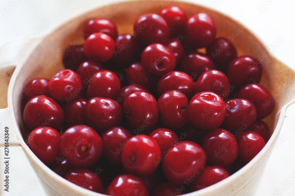 fresh picked red cherry in a large plastic cup on a light background fresh picked red cherry in a large plastic cup on a light background