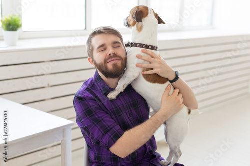 people, pets and home concept - young man playing with jack russell terrier puppy on white background