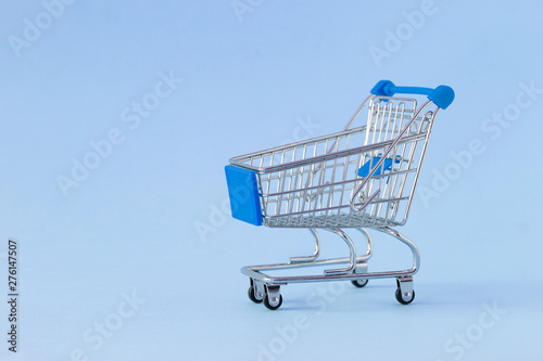 Empty shopping cart on colored background. Close-up of shopping trolley on with some copy space. Consumer concept. Online shopping concept. Black Friday and Cyber Monday 