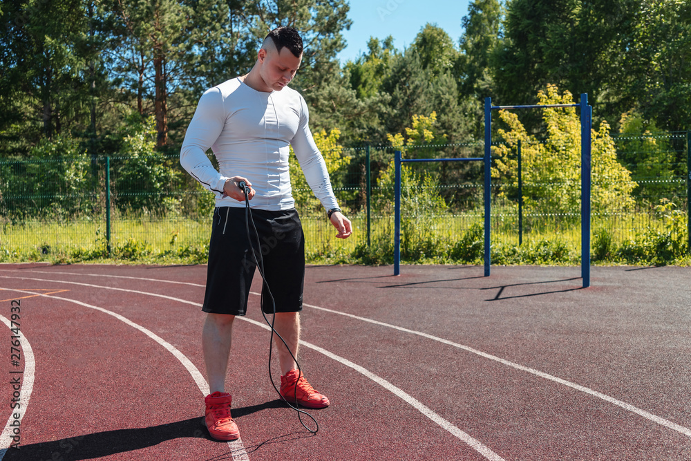 Obraz premium athletic man at the stadium with a rope. Healthy lifestyle. Sport activities on the street