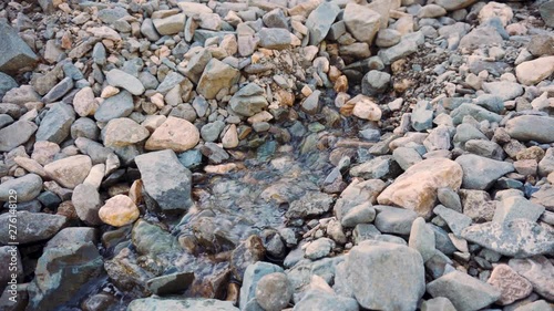 The water flow breaks out from under the stones. photo