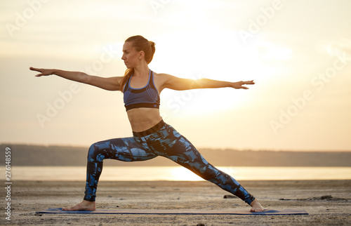 Yoga and fitness. Young woman practicing morning meditation and stretching in nature at the beach