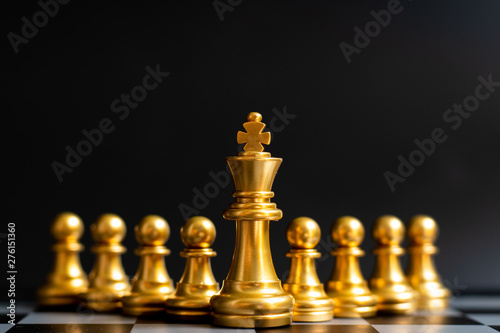 Gold king chess piece stand in front of pawn on black background (Concept of leadership, management)