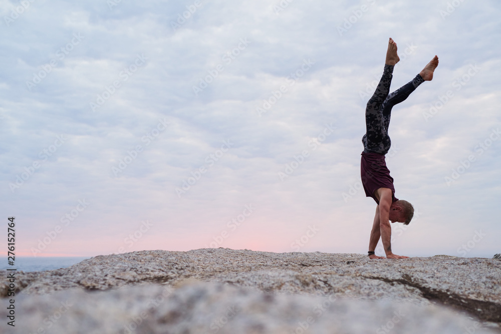 Man doing a hand stand while practicing yoga at dusk Man doing a hand stand while practicing yoga at dusk