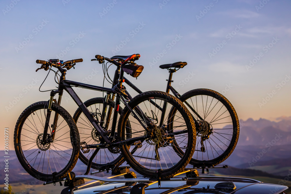 Car transporting bicycles on the roof. Bikes on the trunk. Summer activities concept. Mountains landscape.