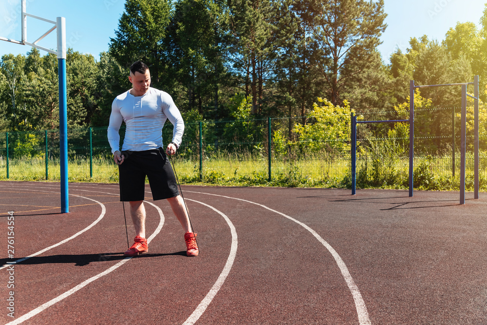 Obraz premium athletic man at the stadium with a rope. Healthy lifestyle. Sport activities on the street