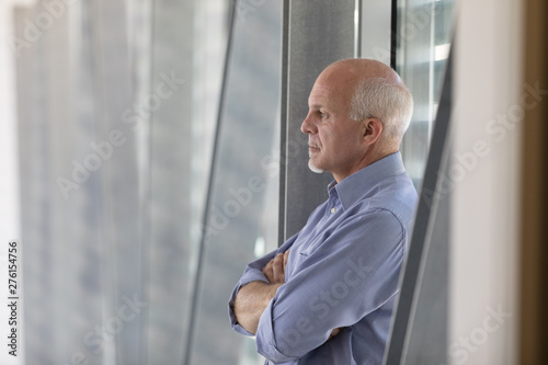 Senior grey-haired man standing deep in thought photo