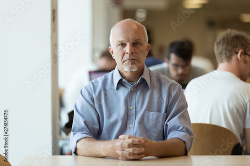 Obraz na plátně Serious senior man sitting alone in a cafeteria