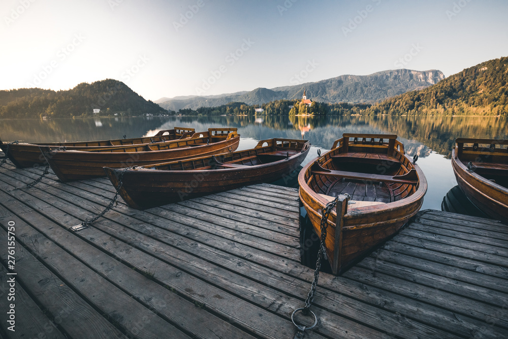 wooden boats at lake bled on a pier in summer during sunrise sunset