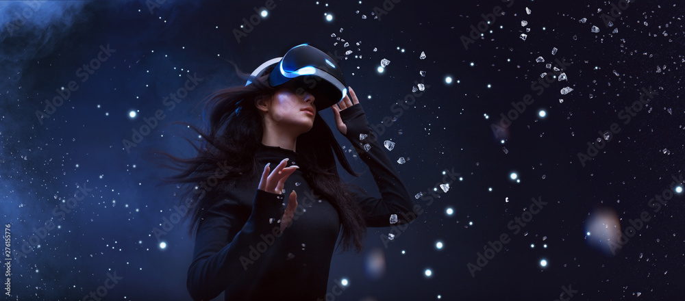 Naklejka premium Beautiful woman with flowing hair in futuristic dress over dark background. Girl in glasses of virtual reality. Augmented reality, game, future technology concept. VR.