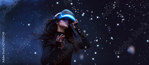 Beautiful woman with flowing hair in futuristic dress over dark background. Girl in glasses of virtual reality. Augmented reality, game, future technology concept. VR. photo