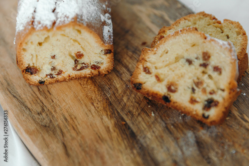 Raisin cake, dusted with icing sugar. Cupcake with raisins on a wooden board.