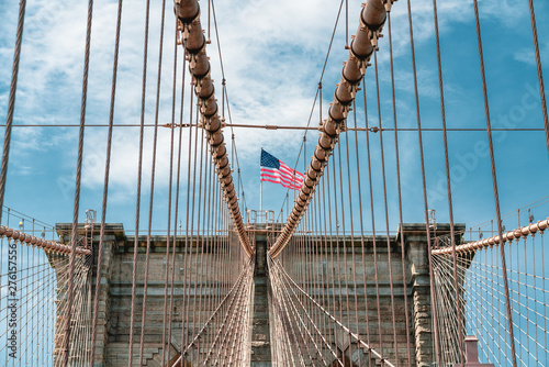 Brooklyn Bridge and American Flag Against Cloudy Blu Sky, New York City.
