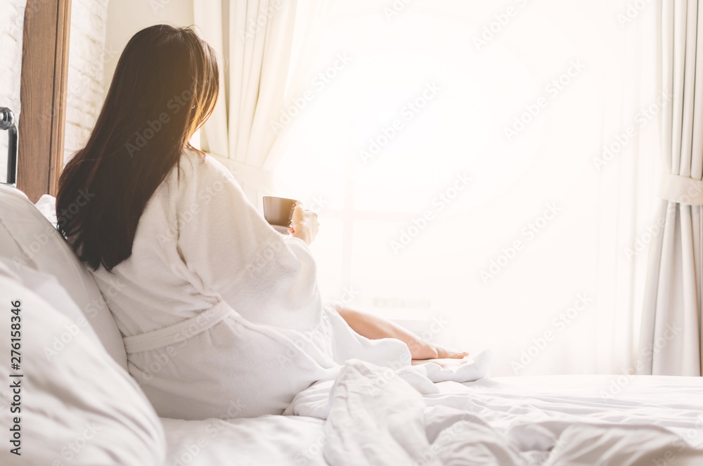 asian woman relaxing in the hotel room, drinking morning coffee, copy space - obrazy, fototapety, plakaty 