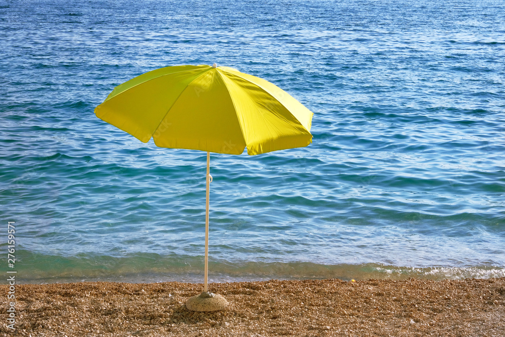 Yellow umbrella on summer beach. Sea beach with sun umbrella waiting for tourists. Happy summer vacations concept.