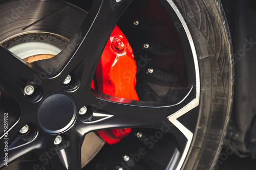 Red brake pads and discs of modern car with black alloy discs.