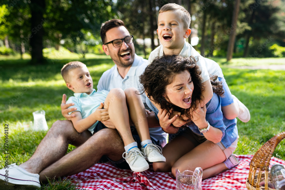 Fototapeta premium Happy young family playing on the grass in the park and enjoying picnic