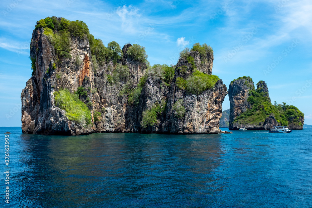 A seascape of a small limestone Thai island in the Andaman Sea, with the flag of Thailand in thA seascape of a beautiful small limestone Thai island in the sparkling Andaman Sea, small boats around