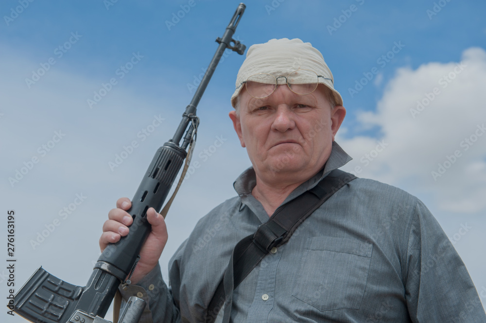elderly man, war veteran, chooses sniper rifle with telescopic sight in gun shop. Pensioner wants to protect your home. concept of weapons for self-defense elderly man, war veteran, chooses sniper rifle with telescopic sight in gun shop. Pensioner wants to protect your home. concept of weapons for self-defense