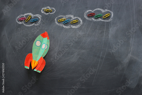 education. Back to school concept. rocket cut from paper and painted over blackboard background. top view, flat lay