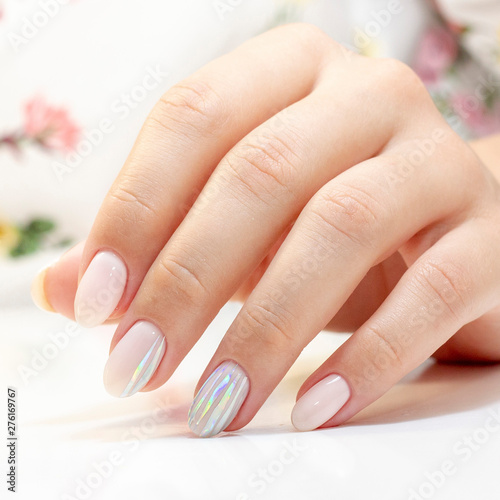manicure. the manicurist made a manicure and gel polish on the clients nails in gentle tones with stripes of foil gloss