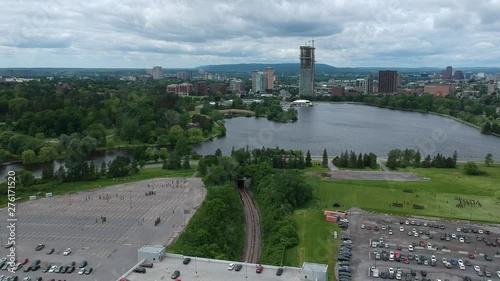 Drone footage high above Ottawa facing the train tracks through Carelton University with a train going by and the Queens Guards Training on  fields near Dows Lake and the O-Train. photo