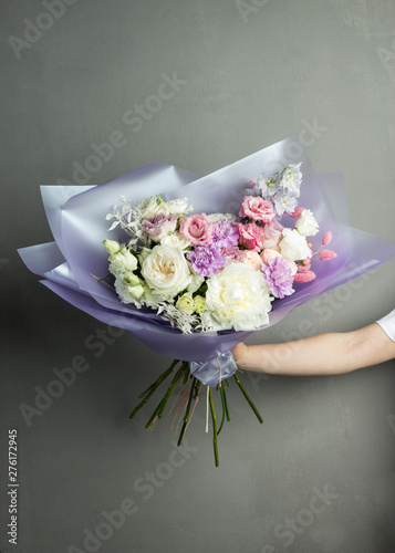 bouquet of flowers in their hands, in purple paper packaging, large lush flowers