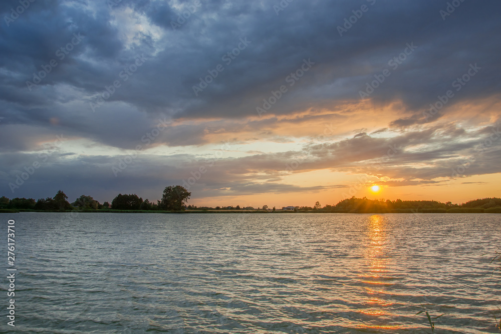 Sunset over the water and dark clouds in the sky