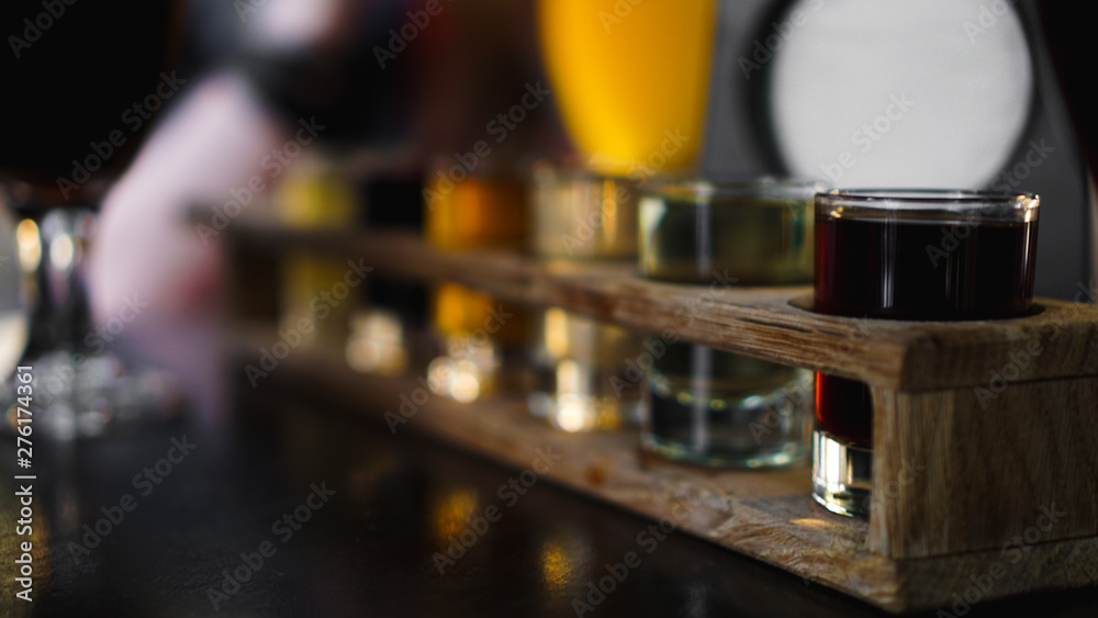 Multicolored transparent cocktails, a set of shots in one row, six servings on a wooden stand, substrate. Drink for the menu restaurant, bar, cafe Multicolored transparent cocktails, a set of shots in one row, six servings on a wooden stand, substrate. Drink for the menu restaurant, bar, cafe