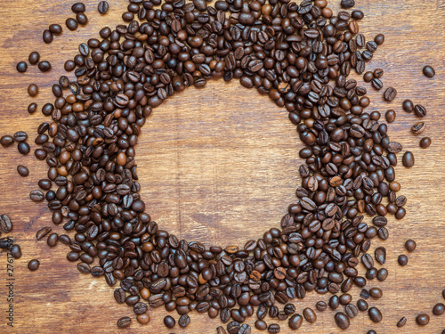 Circle frame made of coffee beans on wooden background. View from above. Coffee background