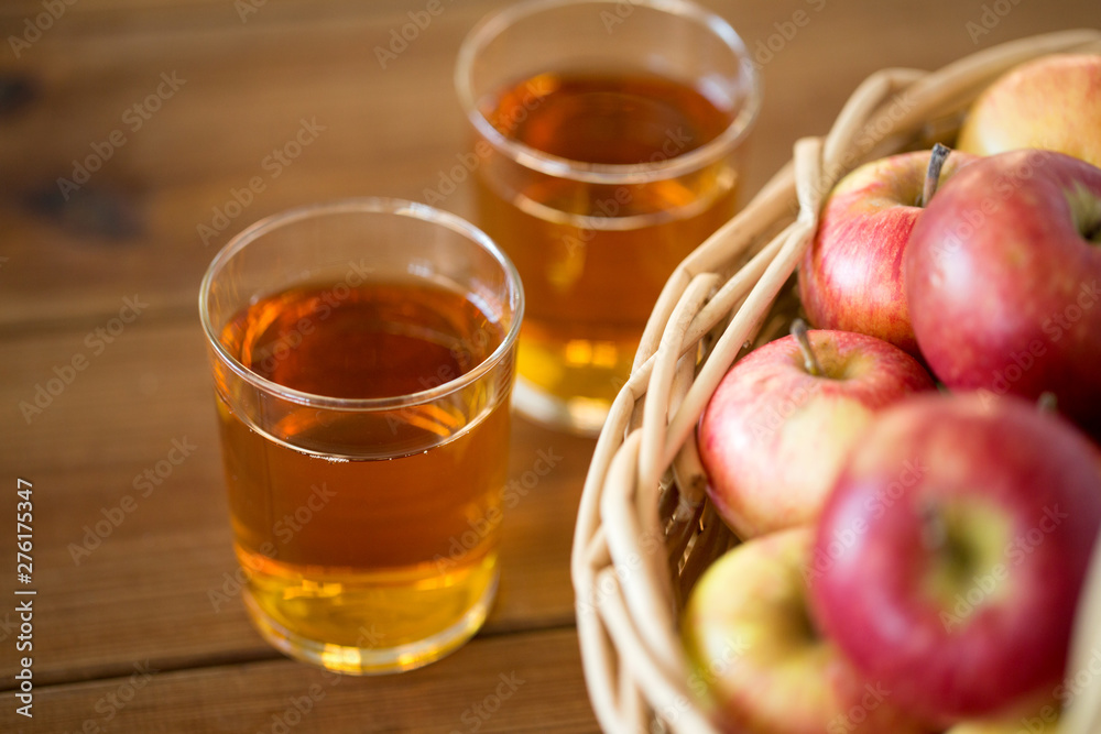 fruits, food and harvest concept - apples in wicker basket and glasses of juice on wooden table fruits, food and harvest concept - apples in wicker basket and glasses of juice on wooden table