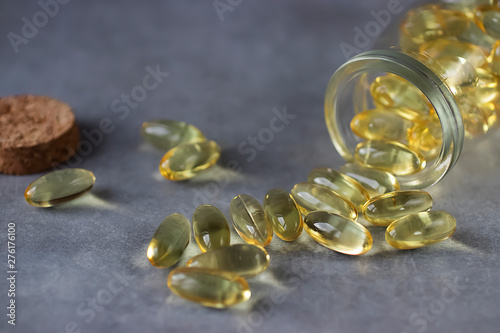 Yellow transparent gelatin capsules on a gray background. Omega-3, Omega-6, Omega-9 fatty acids. The concept of medicine and pharmacology.