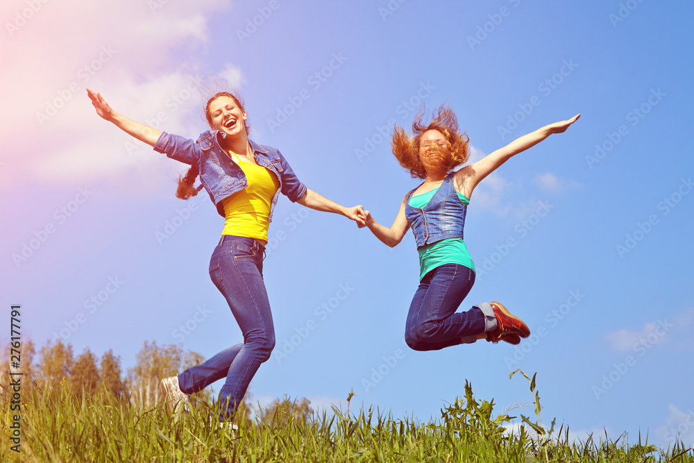 two pretty young women jumping on the sky background. happy girls outdoor. two pretty young women jumping on the sky background. happy girls outdoor.