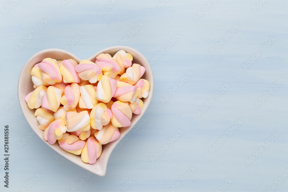 Marshmallows on blue background with copyspace. Flat lay or top view. Background or texture of colorful mini marshmallows. Marshmallows on blue background with copyspace. Flat lay or top view. Background or texture of colorful mini marshmallows.