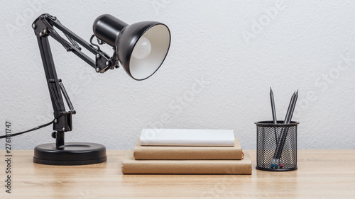 Table lamp on the table with books and pencils. Light background.