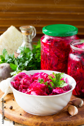 Homemade preserving. Fermented food. Salad Cabbage with Beetroot on the kitchen wooden background.