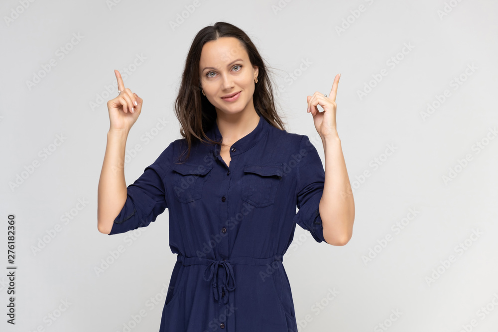 Portrait of a young pretty brunette woman of 30 years old in a simple plain blue dress with dark hair. Standing right in front of the camera, talking, showing hands, demonstrating emotions. Portrait of a young pretty brunette woman of 30 years old in a simple plain blue dress with dark hair. Standing right in front of the camera, talking, showing hands, demonstrating emotions.