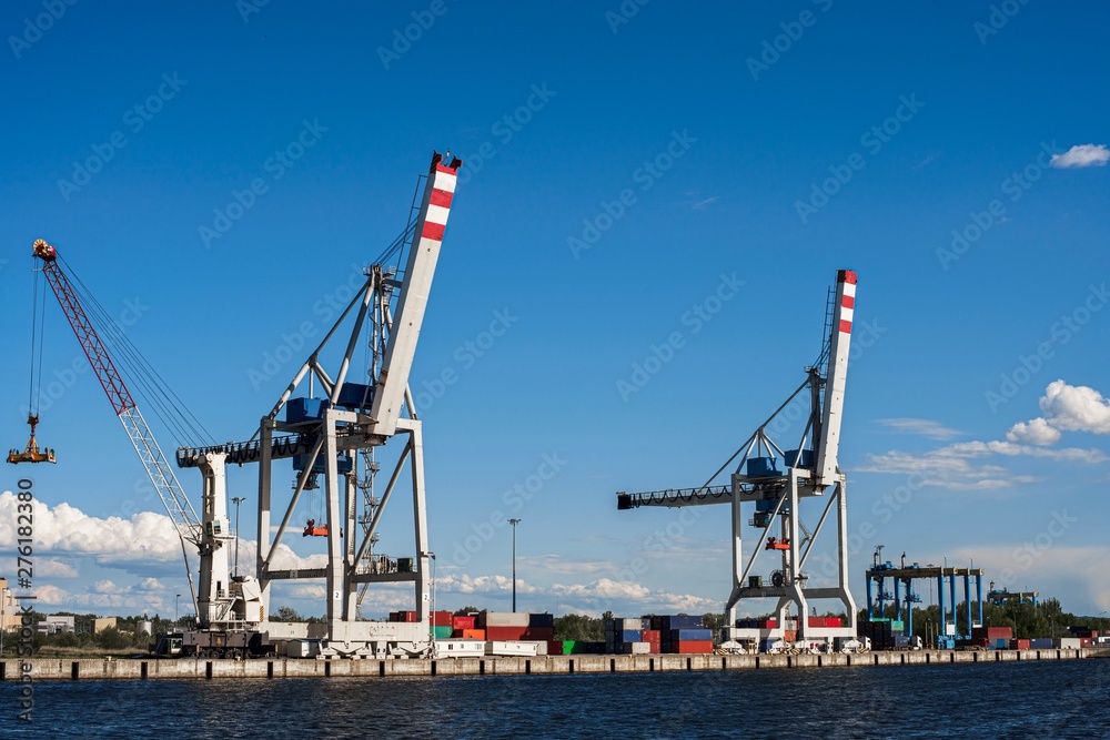 Fototapeta premium Huge crane for loading containers in the cargo terminal of sea port. Summers clear dday. Blue sky. Copy space.
