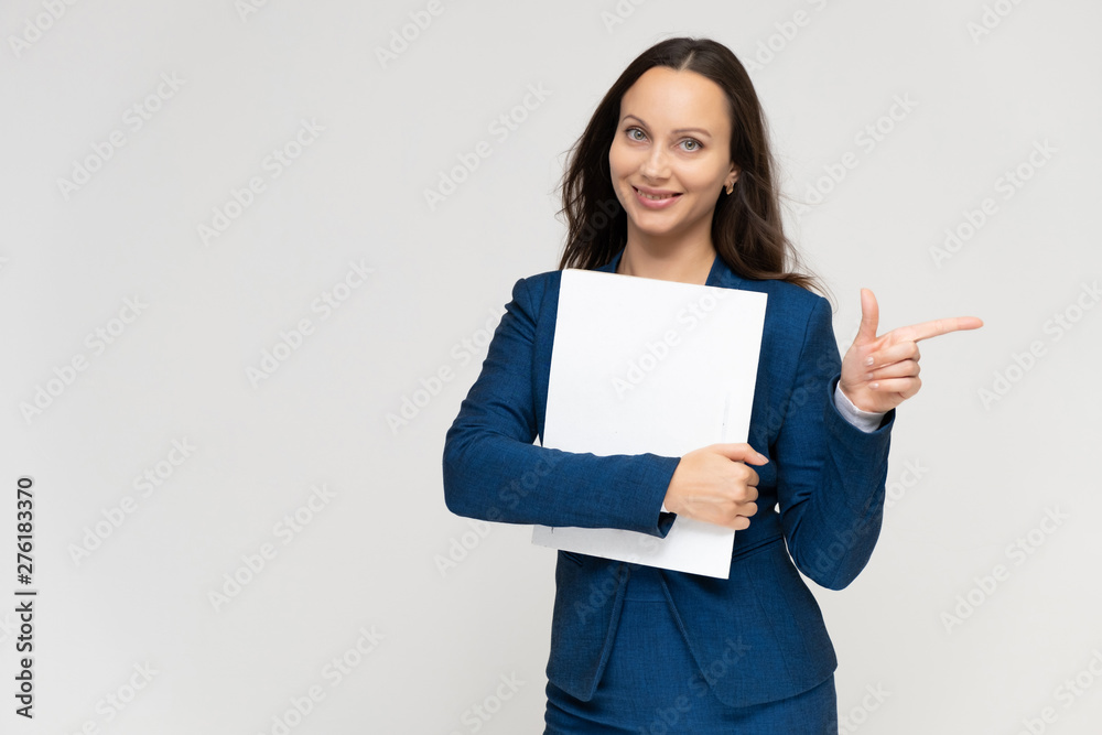 Portrait of a young pretty brunette manager woman of 30 years in a business blue suit with beautiful dark hair. Standing with a folder on a white background, talking, showing hands, with emotions Portrait of a young pretty brunette manager woman of 30 years in a business blue suit with beautiful dark hair. Standing with a folder on a white background, talking, showing hands, with emotions
