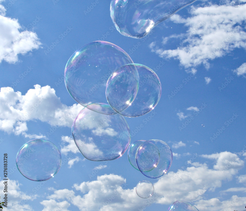 big transparent bubbles fly in a cloudy blue sky
