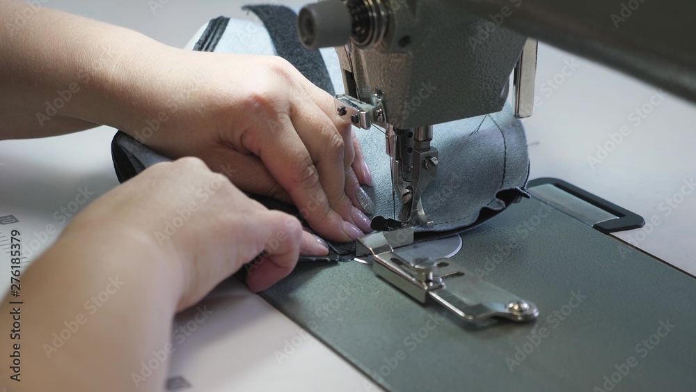 needle of the sewing machine in motion, close-up. needle of sewing machine quickly moves up and down. process of sewing leather goods. Tailor sews black leather in sewing workshop.