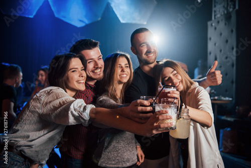 Cheerful mood. Group of young friends smiling and making a toast in the nightclub