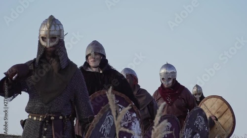 Group of medieval vikings with arms and shields going on the winter meadow. photo