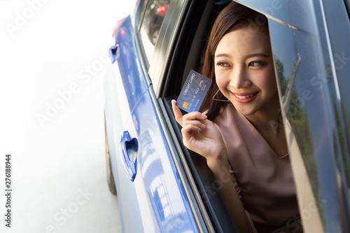 Happy young Asian woman holding payment card or credit card and used to pay for gasoline, diesel, and other fuels at gas stations, Driver with fleet cards for refueling car