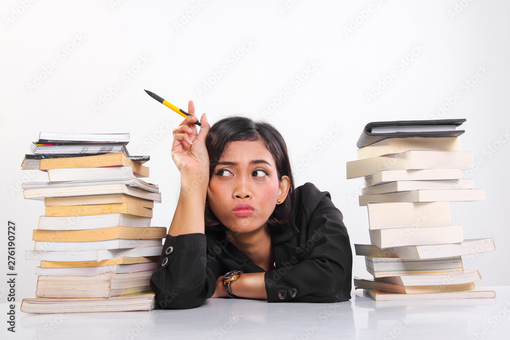 Schoolgirl feels bored, resting between stacks of text books Schoolgirl feels bored, resting between stacks of text books