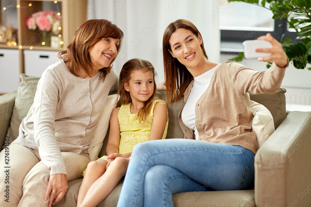 family, generation and technology concept - happy mother, daughter and grandmother taking selfie by smartphone at home family, generation and technology concept - happy mother, daughter and grandmother taking selfie by smartphone at home