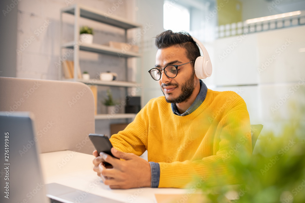 Bearded manager using smartphone in office