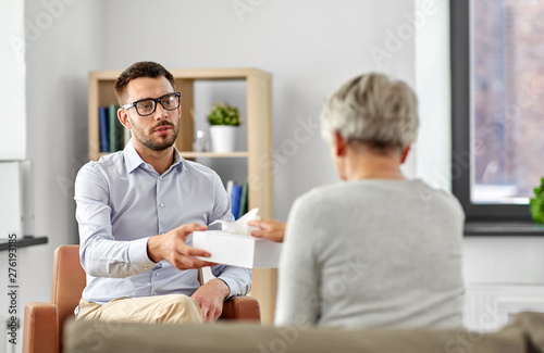 geriatric psychology  mental therapy and old age concept - psychologist giving tissues to senior woman client at psychotherapy session