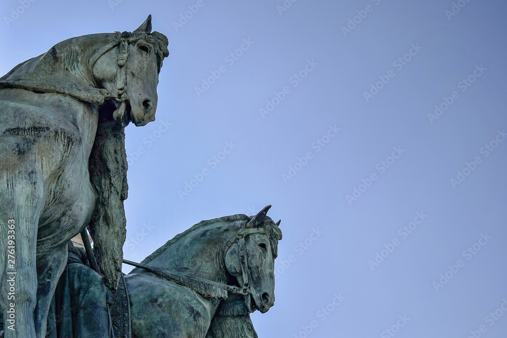 Fragment of the Millennium Monument on the Heroes' Square in Budapest, Hungary. Side view on statue horses of  the chieftains of the Magyars against a blue sky. Close-up. Selective focus. Copy space.