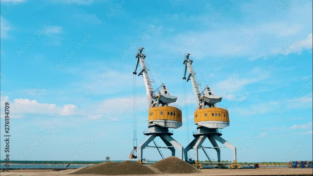 Two working cranes unload breakstones in a port. Two working cranes unload breakstones in a port.
